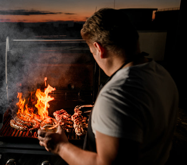 Man cooking over flaming barbecue