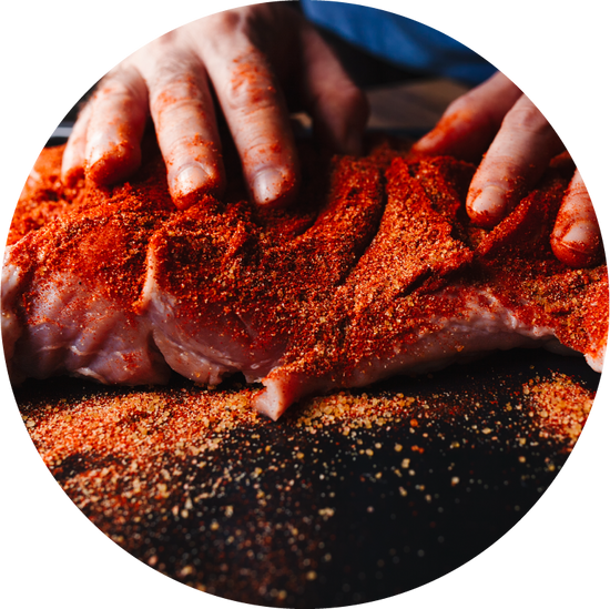 man rubbing meat seasoning rub onto ribs